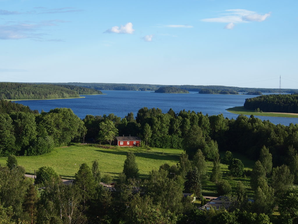 Maisema, jossa on vettä, metsää ja mökki